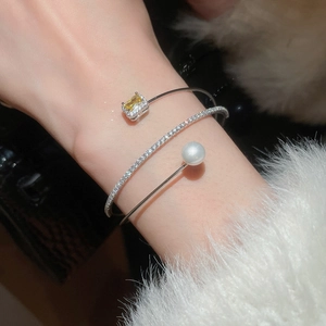 Detail of three-layer silver bracelet with yellow gemstone, zircon pavé, and pearl
