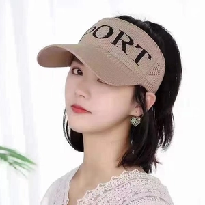 Close-up of khaki knitted sun visor hat with Sport letter print worn by a model