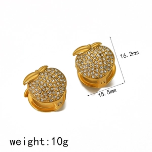 Boucles d'oreilles dorées en forme de fruit avec zircons sur fond blanc