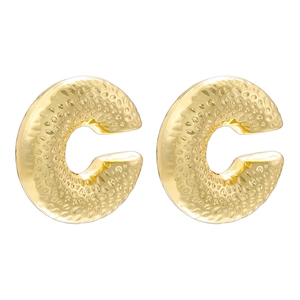 Close-up of golden C-shaped stud earrings featuring vintage hammered metal texture