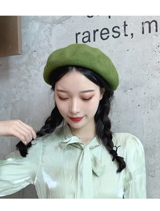 Detail of wool grass green beret on a model against a minimalist studio background