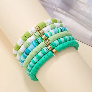 Detail of bohemian polymer clay bracelets with blue green beads on a beige display stand
