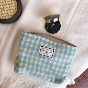 Close-up of blue and yellow plaid cotton makeup bag with Time to Party label on tassel rug