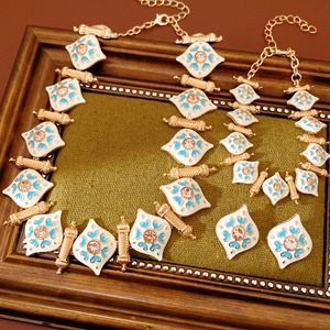 Vintage jewelry set with gold metal, blue patterns and pink stones on green fabric