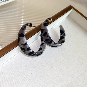 Detailed view of grey leopard print C-shape hoop earrings on a white textured tray