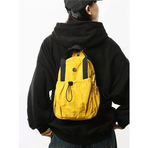 Water-resistant yellow nylon mini backpack shown on model with minimalist sport styling