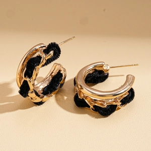 Gros plan de boucles d'oreilles en C avec chaîne dorée et tissu velours noir tressé