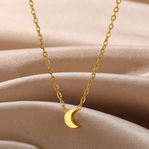 Macro shot of minimalist gold crescent moon pendant on champagne silk fabric background