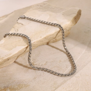 Macro detail of silver stainless steel 3mm oval link chain on a natural stone base