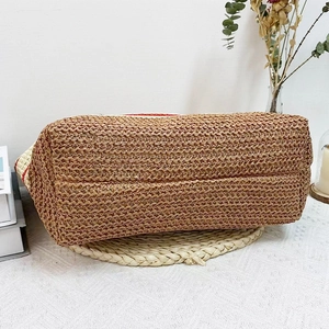 Detailed view of reinforced rectangular bottom on woven straw shoulder beach bag
