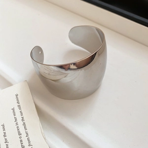 Detailed close-up of a silver knotted open cuff bracelet with a mirror-polished finish