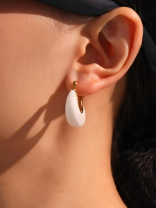 Close-up of model wearing gold-plated U-shaped earring with white resin inlay