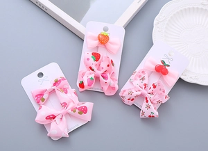 Detailed view of handmade pink ribbon bow hair clips with cute strawberry and cherry patterns
