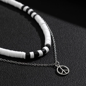 Double-layered necklace with black and white heishi beads and silver peace sign pendant