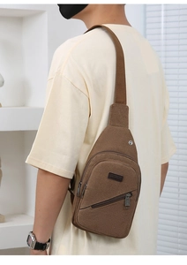 Detail view of brown canvas chest bag with adjustable strap and leather logo patch