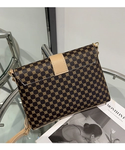 Detail of coffee brown crossbody bag with clover pattern and gold magnetic buckle closure