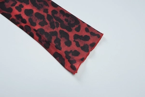 Close-up of red leopard print mesh fabric showing detailed hem stitching and sheer texture