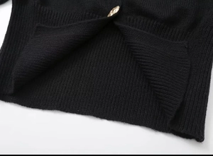 Detailed close-up of black ribbed knit fabric featuring a unique gold irregular metal button