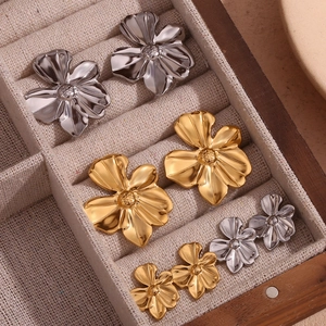 Detailed close-up of 18K gold and silver plated floral stud earrings in a wooden jewelry box