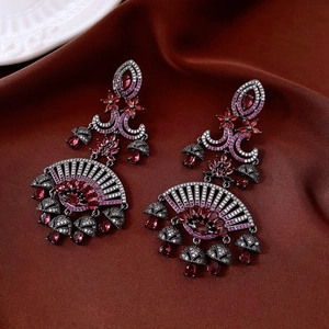 Detailed macro of bohemian style fan-shaped earrings with red gems and long tassels