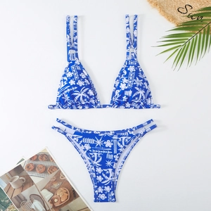 Detailed flat lay of blue tropical floral bikini set with sun motifs and beach accessories