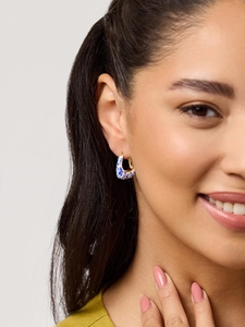 Detail of 18K gold blue and white porcelain enamel hoop earrings worn by a model