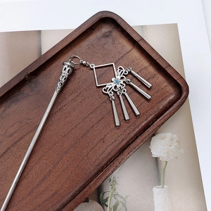 Detail of silver vintage hair pin with tassels and blue beads on wooden tray