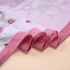 Detail of silk scarf showing elegant purple floral print and smooth satin texture