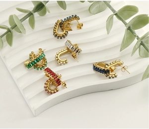 Five pairs of 18K gold U-shaped earrings with colorful zircon stones on white display