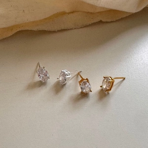 Detail of oval zircon stud earrings in silver and gold plating with four-prong settings