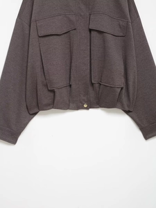 Detail of the knit bomber jacket with large patch pockets and a gold metal button