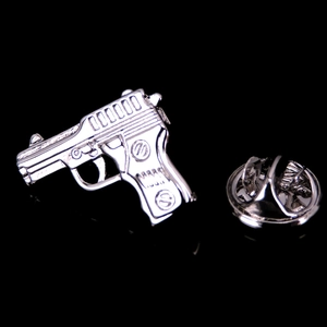 Detailed close-up of a silver pistol brooch with metallic texture and butterfly clutch