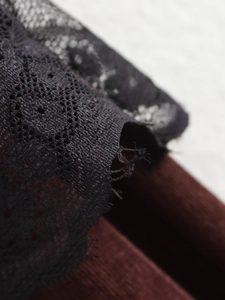 Close-up of intricate black floral lace pattern and mesh texture on elegant trousers