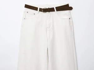 Detail view of high waist white denim trousers with a brown leather belt and metal buckle