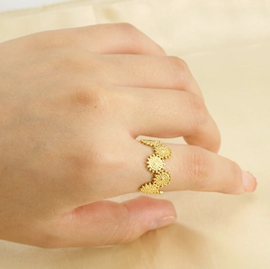 Detailed close-up of golden daisy flower ring band with metallic floral patterns