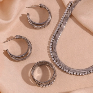 Detailed view of silver herringbone necklace and rhinestone jewelry set on pink silk