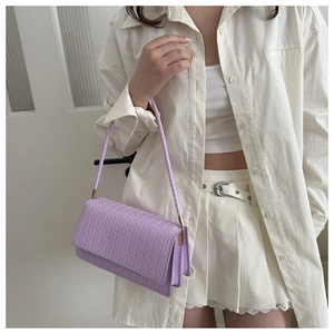 Model wearing a light purple woven crossbody bag with elegant leather texture and gold hardware