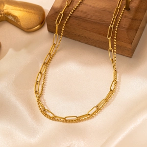 Detail of 18K gold-plated double-layered paperclip and beaded necklace on satin