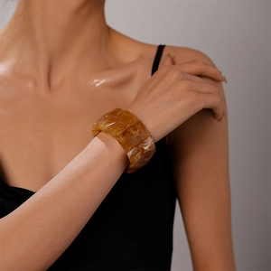 Detail of amber marble acrylic bangle with wide geometric facets worn by a model