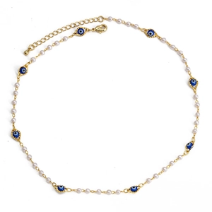 Close-up of golden evil eye necklace with white pearls and blue enamel eye beads