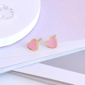 Close-up of pink heart stud earrings with gold metal edges and enamel finish
