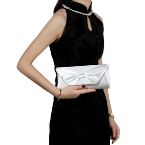 Detailed view of white satin clutch with large bow on elegant black cheongsam