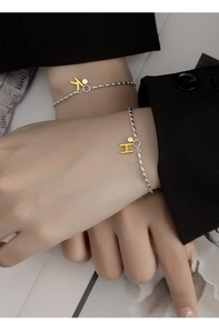 Detail of silver bead bracelets with gold letter K and H pendants and zircon stones