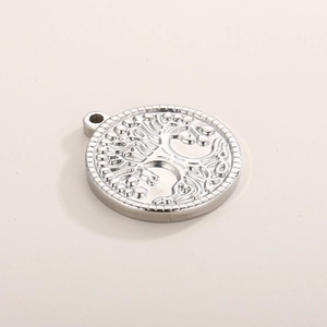 Macro detail of silver tree of life pendant with embossed metallic texture on beige background