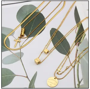 Close-up of layered 18k gold plated necklaces with cross and engraved coin pendants