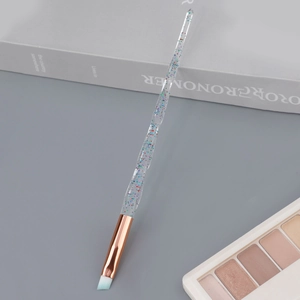 Macro shot of angled eyebrow brush with blue bristles and glitter crystal handle