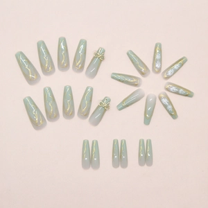 Detailed view of mint green gradient press-on nails with 3D gold bows and white daisies