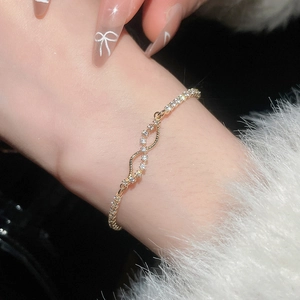 Macro shot of gold infinity wave bracelet with sparkling zircon stones and rope chain detail