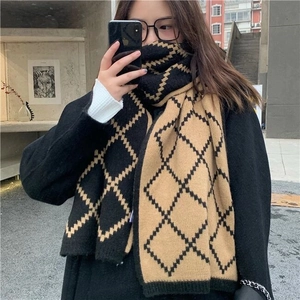 Detail of a black and khaki plaid knit scarf with diamond pattern and contrast design