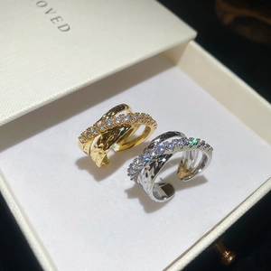 Macro shot of three-layer crisscross rings with zircon pavé and hammered texture in gold and silver